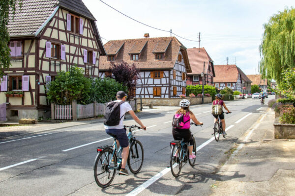 Cyclistes traversant un village alsacien title=
